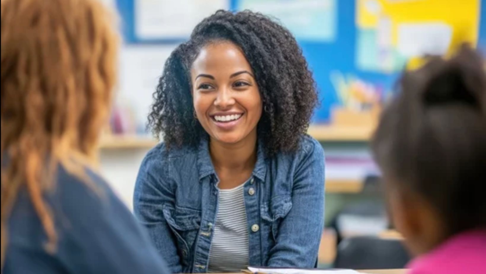 Smiling teacher meeting with a parent and student in a classroom to discuss an individual learning plan.